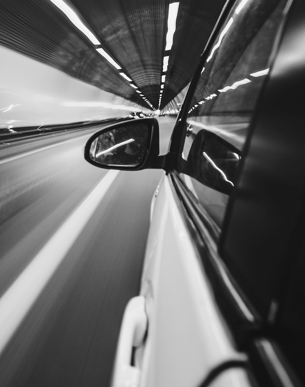 An image of a car's side mirror taken from the backseat of the moving car.