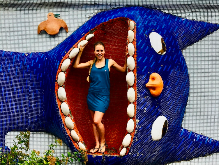 A photograph of Dr Laura Joan Salm standing inside the sculpture of a large cat face.