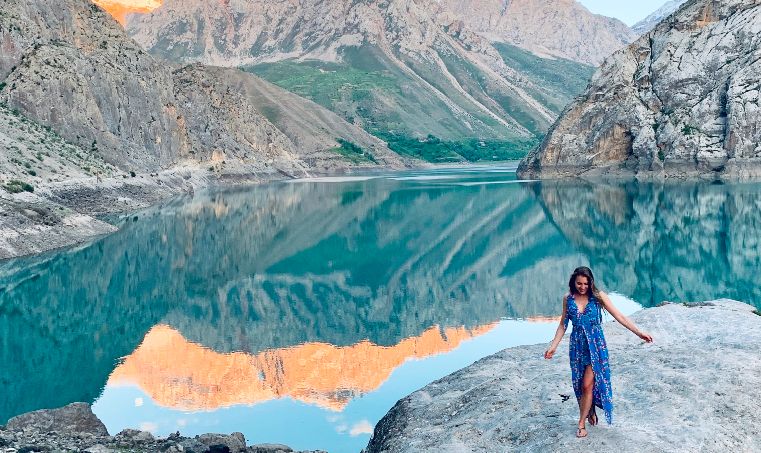 A photograph of Dr Laura Joan Salm over a background of a bright blue lake and mountains.